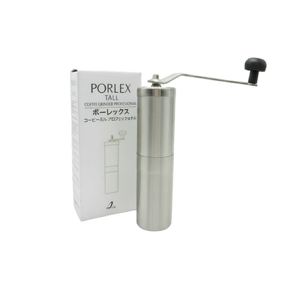 Stainless steel manual coffee grinder next to its packaging on a white background